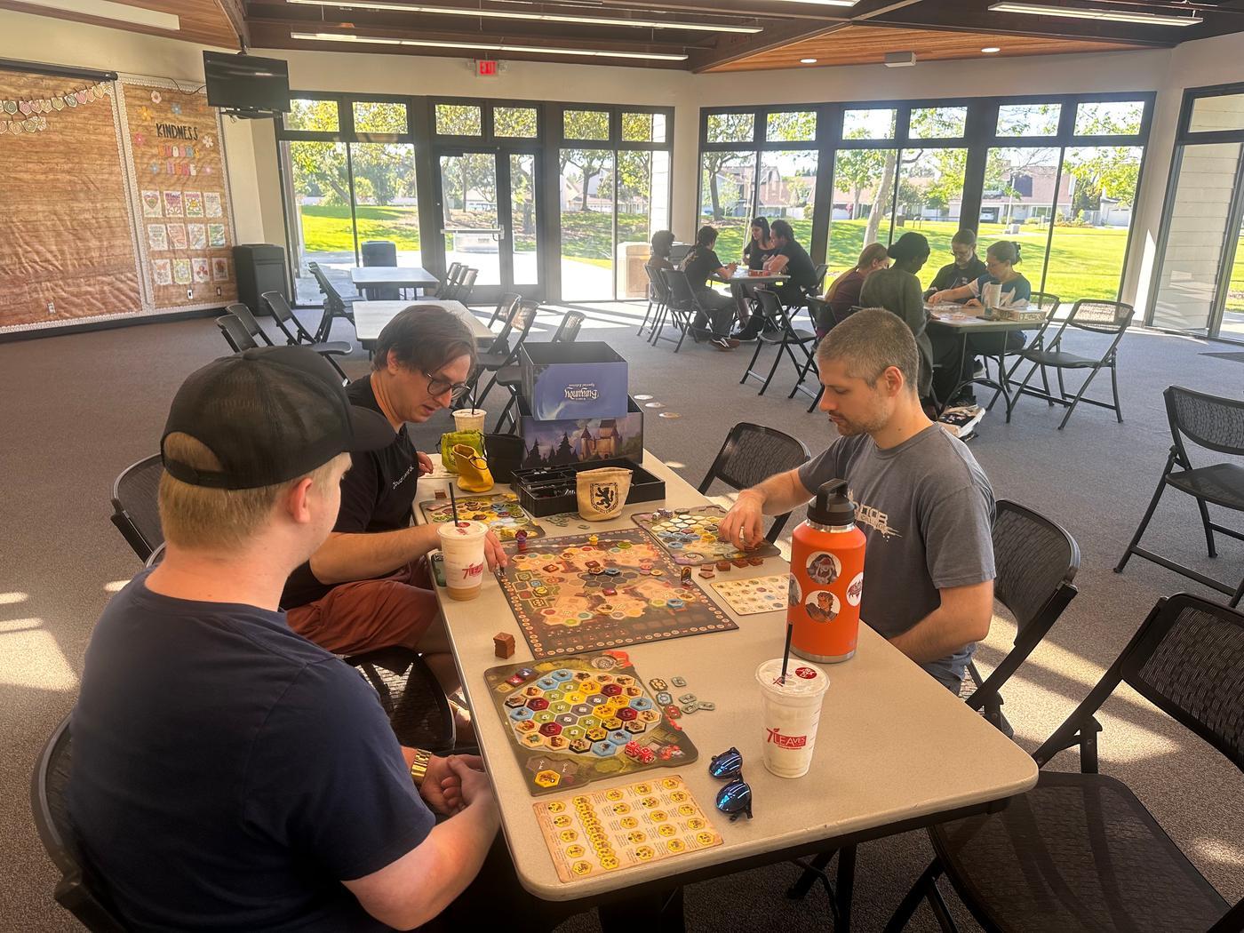 Members gathered around tables playing board games together at a community game night